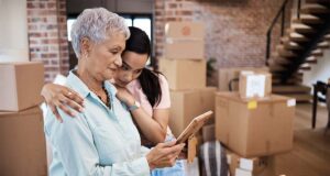 Craft & Communicate | Senior woman looking at a photograph with her daughter while packing boxes on moving day | Senior living blog topics