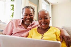 Craft and Communicate | Senior Couple Sitting On Sofa Using Laptop At Home Together